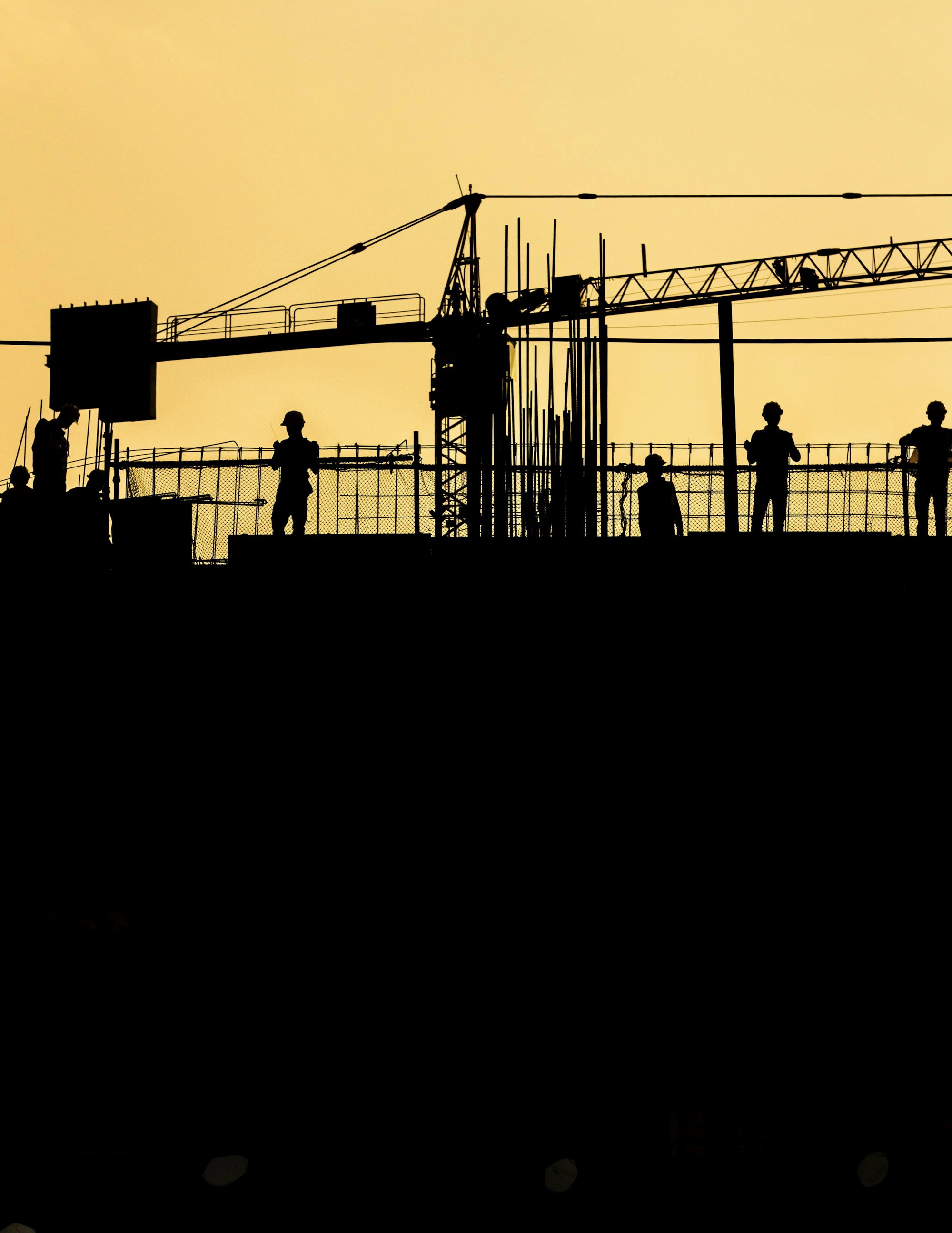 A building crew silhouetted on a site at sunset